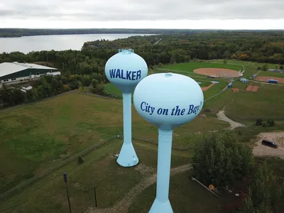 Aerial photo showcasing Walker's twin water towers against lush greenery and serene water backdrop.